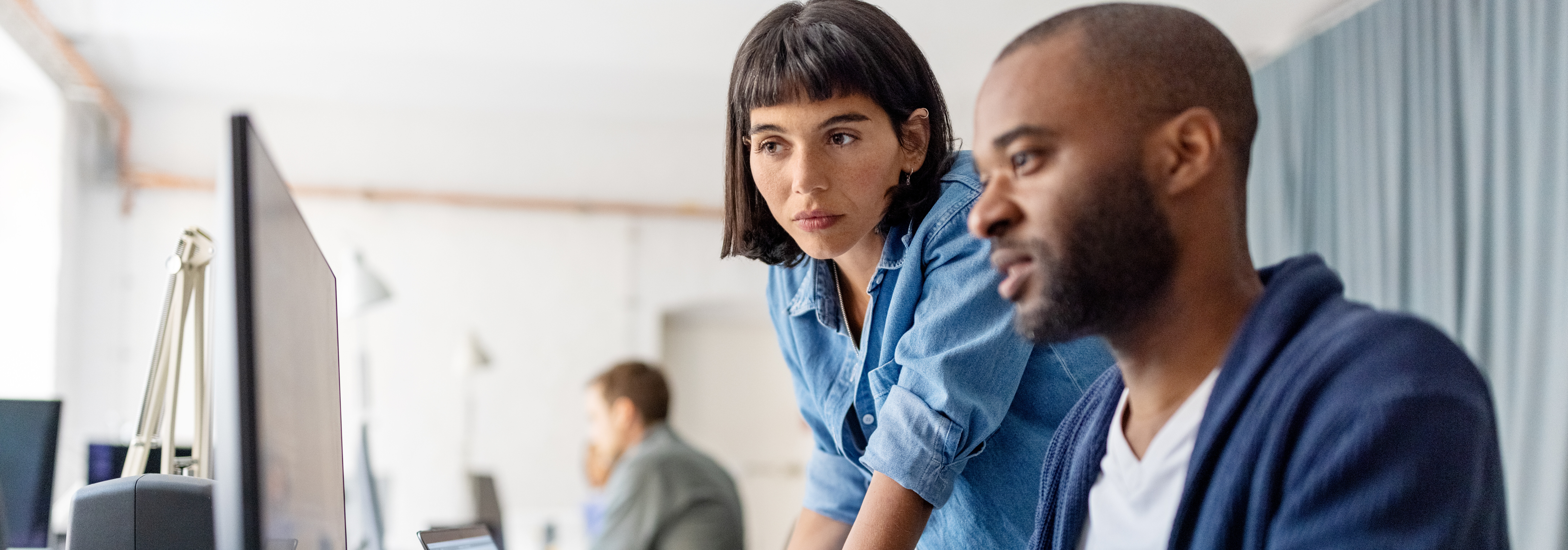 Profesionales trabajando juntos frente a un ordenador en una oficina.