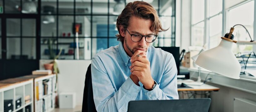 Man reading a laptop screen at his desk