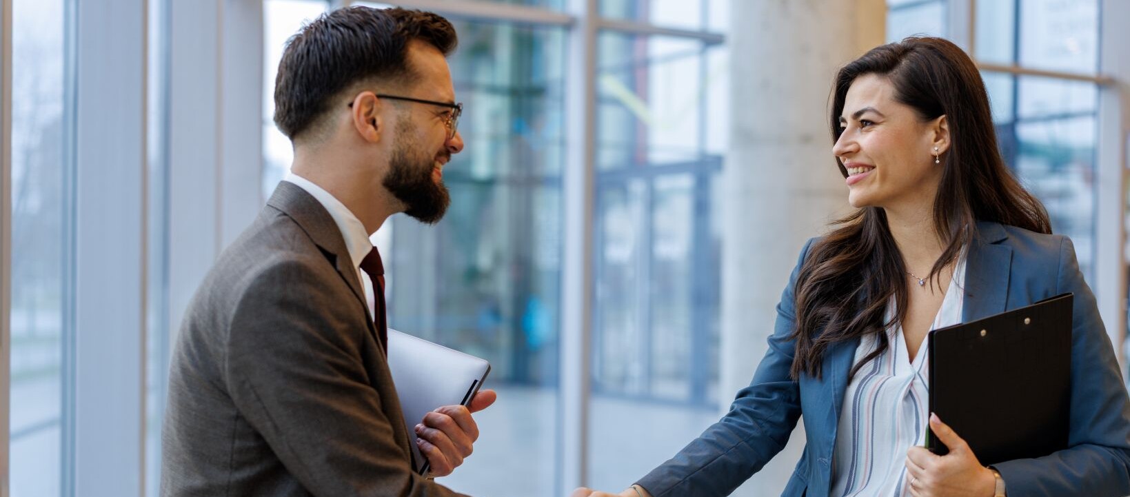 Business professionals shaking hands in a modern office, symbolising a B2B partnership.