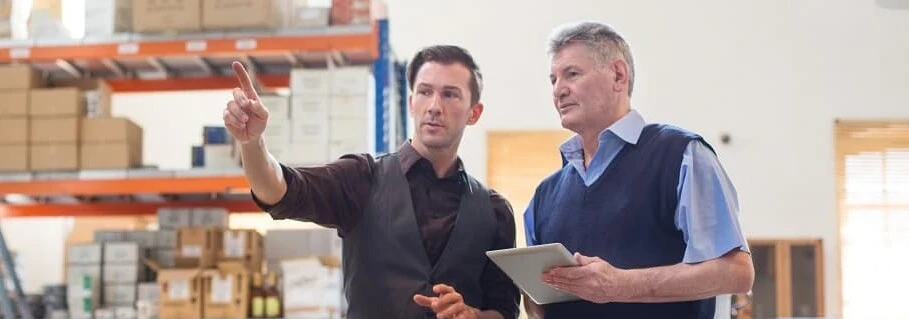 Warehouse managers reviewing stock levels and inventory processes in an industrial storage facility