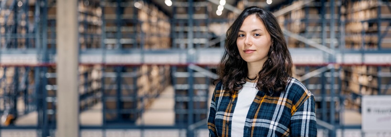 Woman with a clipboard standing in a warehouse with tall storage shelves