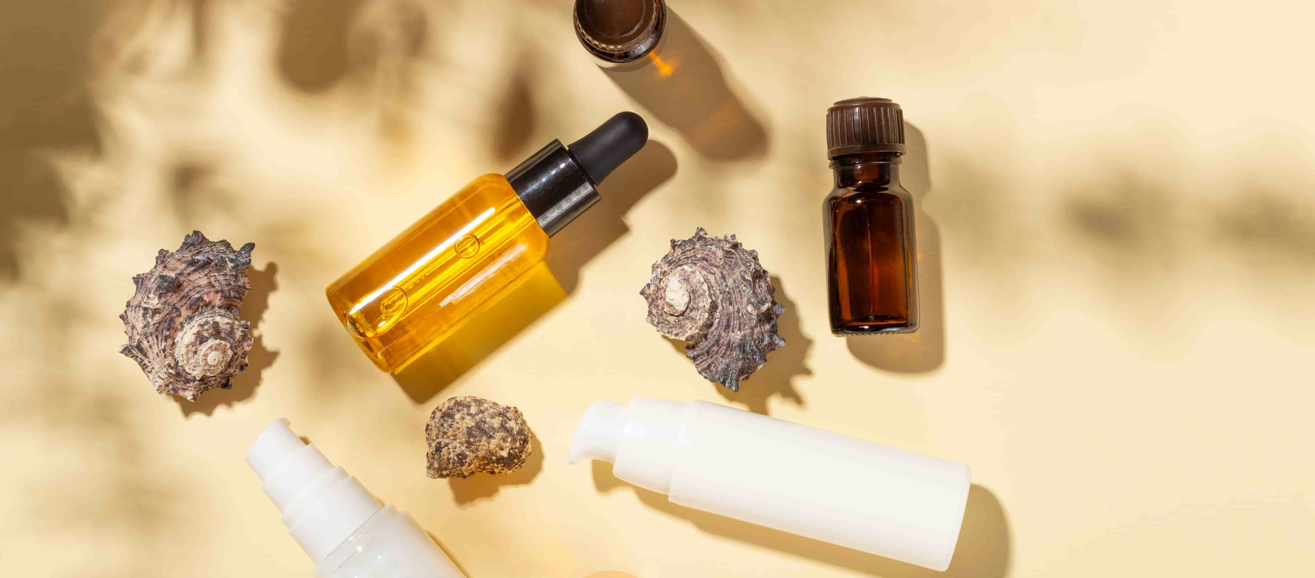 Différents flacons de soins placés autour des coquillages.