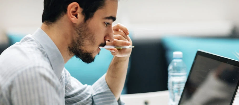 Professional working at a laptop while reviewing information at a desk in an office environment