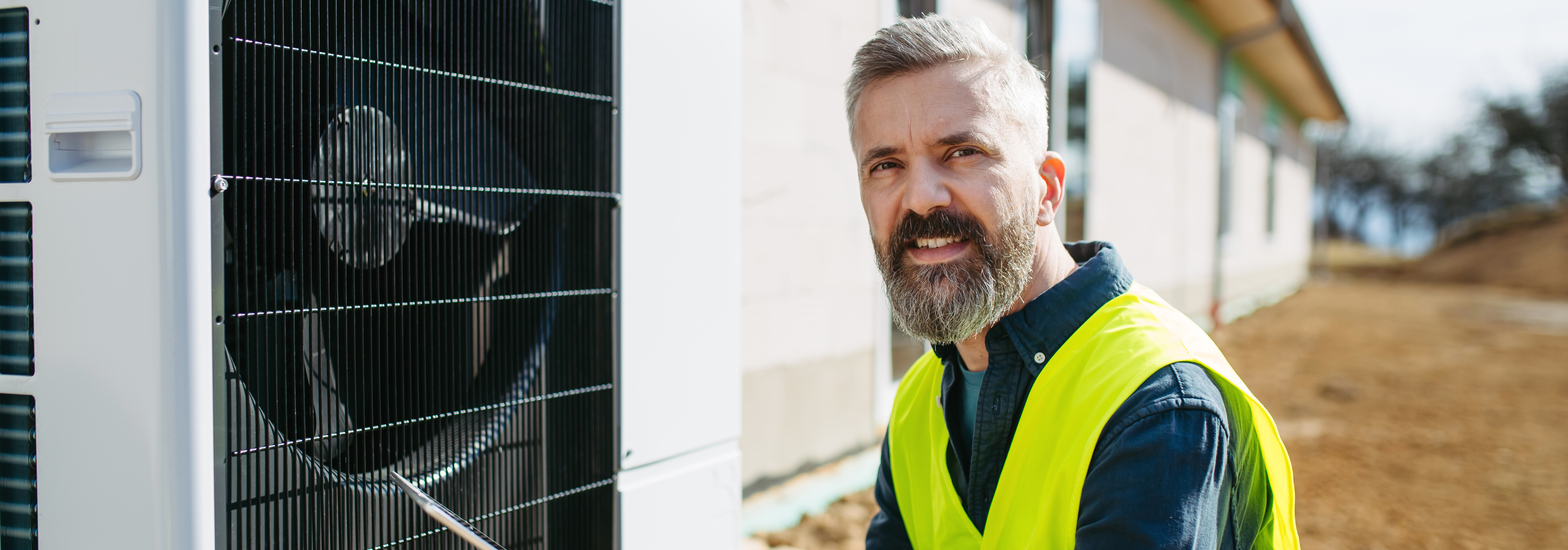 Technicien inspectant une pompe à chaleur extérieure avec une tablette.