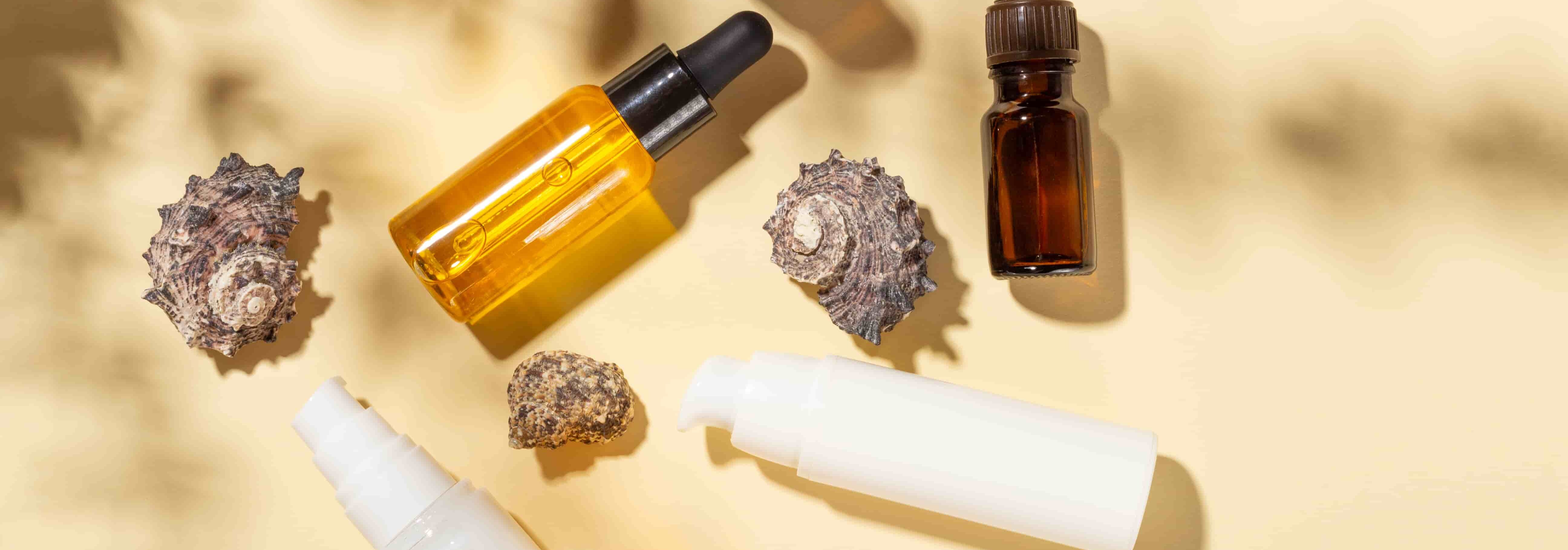 Different skincare bottles placed around shells.