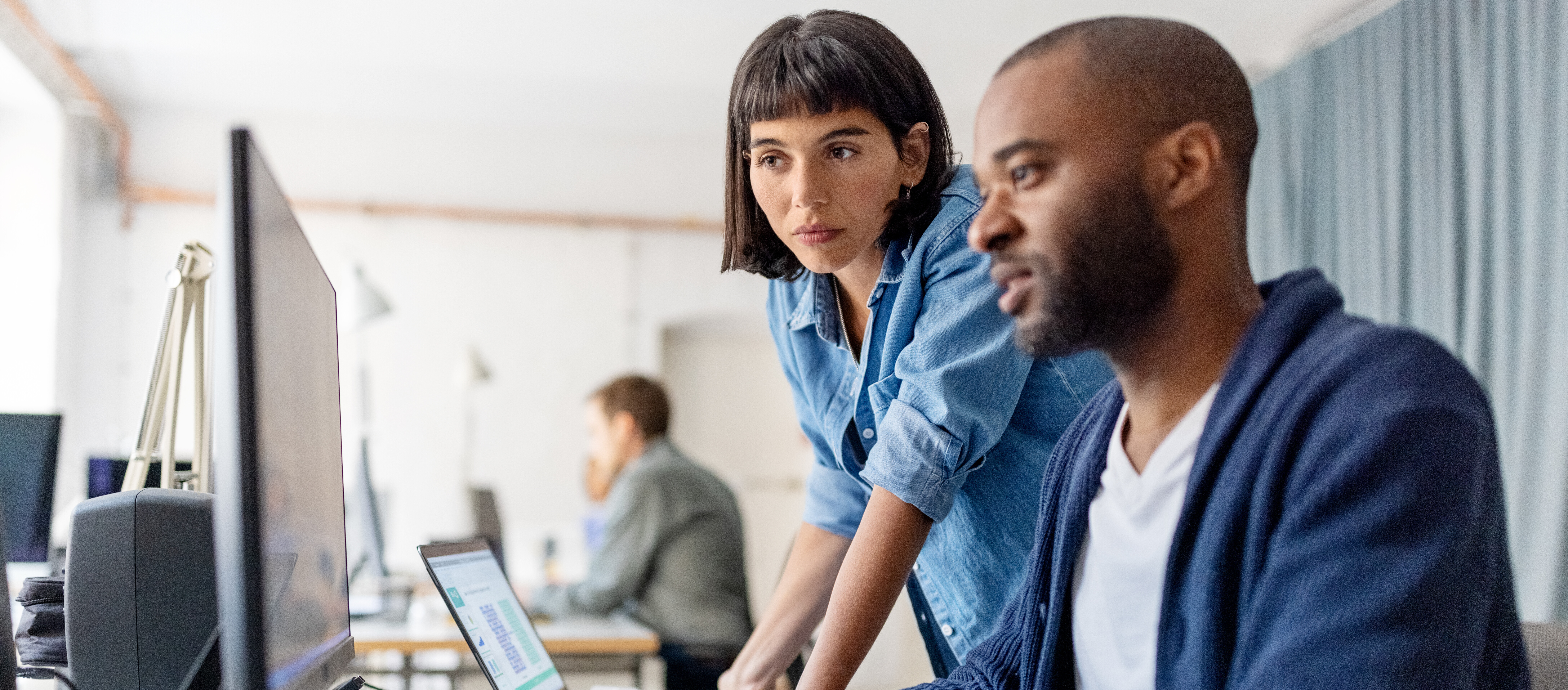 Profesionales trabajando juntos frente a un ordenador en una oficina.