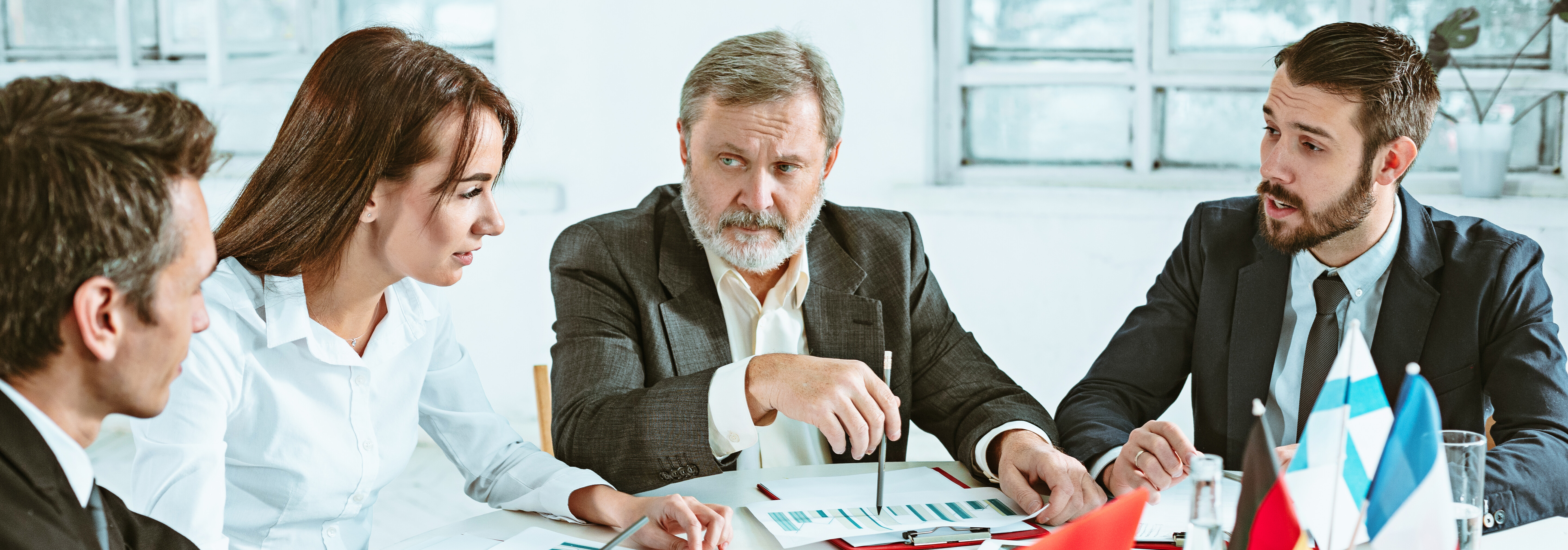 Professionisti aziendali che discutono documenti durante una riunione attorno a un tavolo da conferenza.